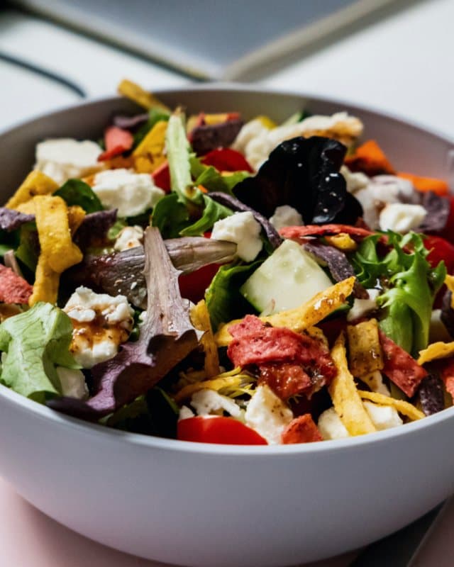 Tigela de salada colorida com folhas, legumes e queijo